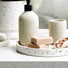 Terrazzo-style bathroom tray with soap bars, dispenser, and bath accessories on a white vanity countertop