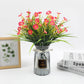 Spray-painted glass vase showcasing fresh flowers on a hotel side table